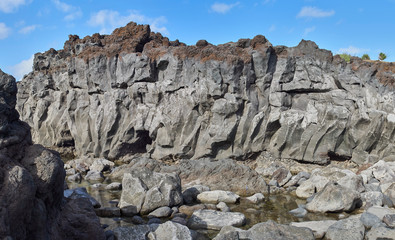 Volcanic sea cliffs, basaltic lava formations at Ponta Dos Capelinhos, submerged in an eruption from under the atlantic ocean in 1957, on Faial island in the Azores.