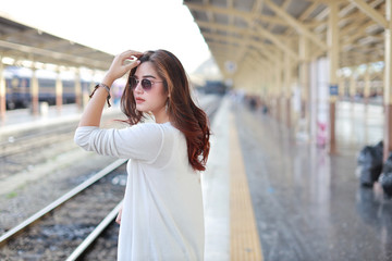 Fototapeta premium back view portrait of young asian woman in white dress with sun glassess standing and pose in train station with smiling and beauty face
