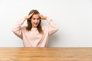 Teenager girl in a table with surprise facial expression