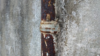rust pipe with a old rust clamp on a concrete wall
