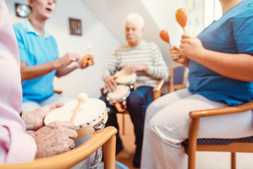 Seniors in nursing home making music with rhythm instruments - 291717970