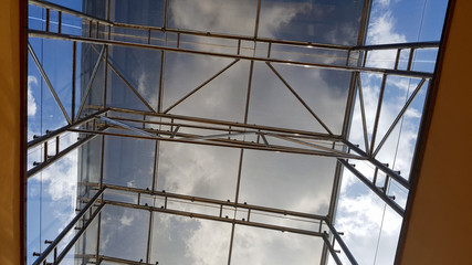 Structural glazing of the facade. Abstract background with glass ceiling elements in a modern building. view of the blue sky through a glass window, separated by lattice elements.