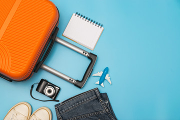 Flat lay orange suitcase with traveler accessories on soft blue background. travel, summer and holiday concept