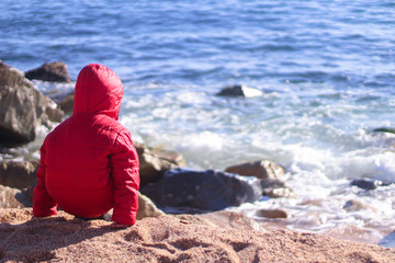 Little boy on the beach in a cold day of winter