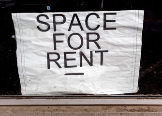 Unappealing SPACE FOR RENT sign posted in dirty window.