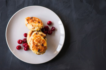 cottage cheese pancakes with cherries and jam on a dark background