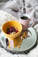 Old fashioned oats with simmered berries and black coffee on bed, breakfast in bed, copy space, cozy mornings