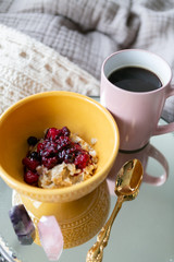 Old fashioned oats with simmered berries and black coffee on bed, breakfast in bed, copy space, cozy mornings