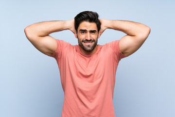 Fototapeta na wymiar Handsome young man in pink shirt over isolated blue background frustrated and takes hands on head