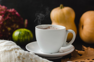 Autumn or winter concept. A cup of hot latte with spices on a black background. Autumn Composition of dry leaves, pumpkins, autumn flowers and coffee on a black background