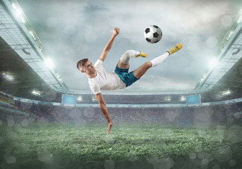 Fototapeta na wymiar Soccer player on a football field in dynamic action at summer day under sky with clouds. Sporty man is shooting the ball outdoor. Sport, game concept.