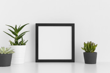 Black square frame mockup with a various types of succulent plants on a white table.
