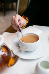 Woman stirring milk and sugar in tea