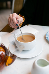 Woman stirring milk and sugar in tea