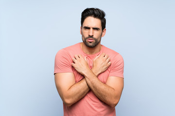 Handsome young man in pink shirt over isolated blue background freezing