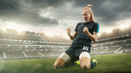 Fototapeta na wymiar Taste or win. Young female soccer or football player in sportwear celebrating the goal in action at the stadium while gameplay. Concept of healthy lifestyle, professional sport, hobby, motion