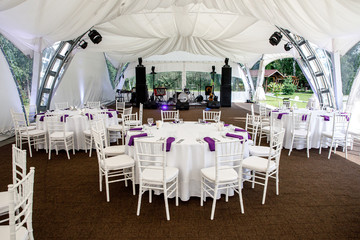 Interior of a event tent decoration ready for guests. Served round banquet table outdoor in marquee