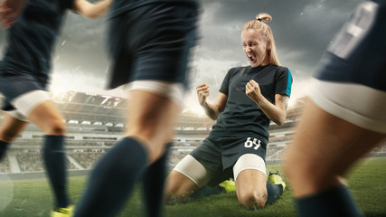 Taste or win. Young female soccer or football player in sportwear celebrating the goal in action at...