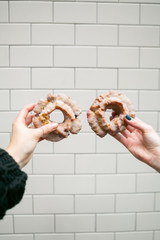 two girls holding out old fashioned blueberry cake donuts, white tile background, copy space