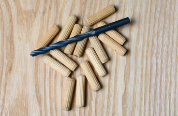 wooden pins and drill bit lie on a wooden surface