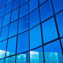 facade of modern office building in glass and steel with reflections of blue sky