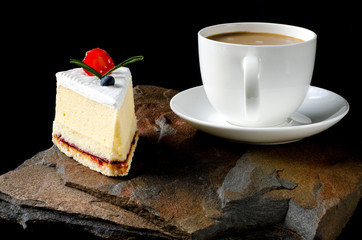 Fruit cake with cherries, grapes and plum stands on a wild stone next to a white cup of coffee with a foam