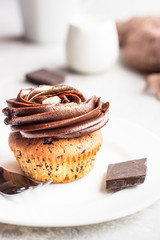 Cupcake or muffin with chocolate with chocolate swirl icing on light grey background. Delicious dessert.