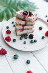 Slice of classic cheesecake with fresh berries on the white plate - healthy organic summer dessert.