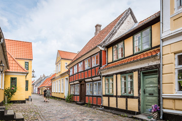 Fototapeta premium two persons walking at the end of an idyllic cobblestone street with old half timbered houses