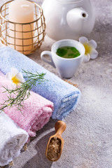 Obraz na płótnie Canvas Color towels with flower, spoon of salt, on bamboo mat, bath spa treatment and green tea on stone table, copy space