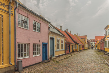 two persons walking at the end of an idyllic street with cobblestone and colourful houses