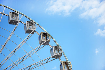 Ferris wheel on cloudy sky background, close up.