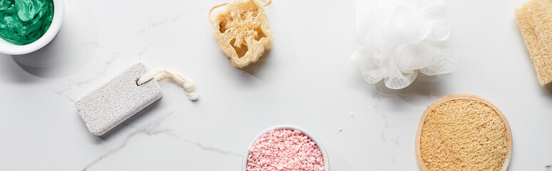 panoramic shot of bath sponges, loofah, pumice stone and cups with natural beauty products on...