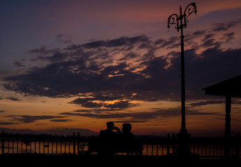 Sunset over a lake with a park bench in front