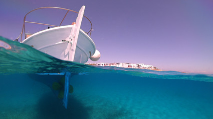 Above and below underwater photo of traditional fishing boat docked in turquoise clear sea, Mykonos island, Cyclades, Greece