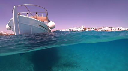 Fototapeta na wymiar Above and below underwater photo of traditional fishing boat docked in turquoise clear sea in port of Koufonisi island, Small Cyclades, Greece