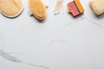 Fototapeta na wymiar top view of homemade soap, bath sponges, ear sticks and body brush on marble surface