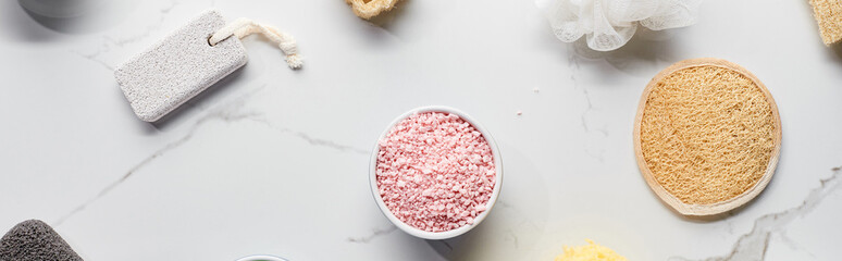panoramic shot of pink bath salts near face sponge and pumice stone on marble surface