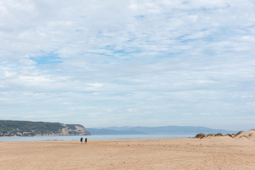 Fototapeta na wymiar Dos persona caminan sobre la arena de la playa