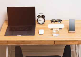 Desk. Workplace at home. On the wooden table is a glass of water, phone, alarm clock.