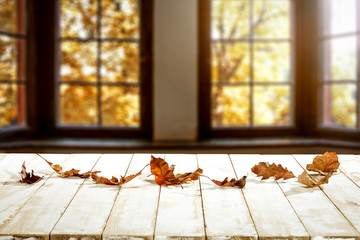 Desk of free space and white table with autumn leaves 