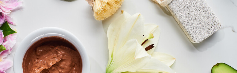 panoramic shot of brown clay mask, pumice stone and white flower on marble surface