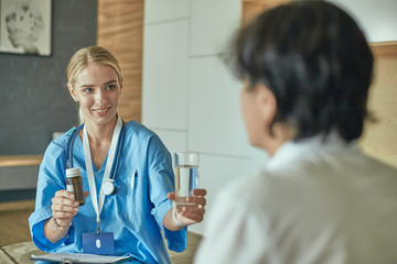 Beautiful smiling woman the doctor in a bottle of pill offers t