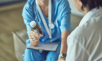Beautiful smiling woman the doctor in a bottle of pill offers t