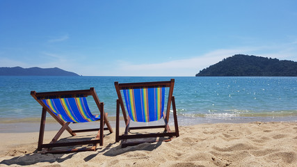 Two colorful empty beach chairs on the beach near the water