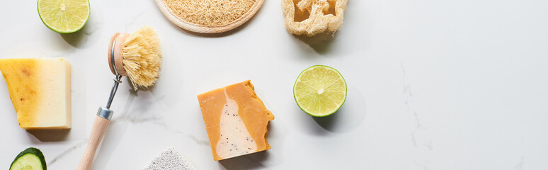 panoramic shot of natural soap, body brush, loofah and fresh lime on marble surface