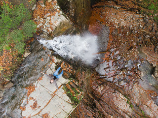 man standing on the cliff looking at waterfall autumn time