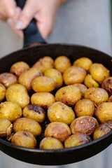 girl holds pan with whole baked potatoes.