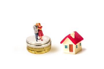 miniature older couple family stand on stack coins with tiny home isolate on white background,  Image for real-estate management  concept.