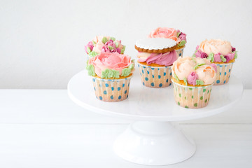 Cupcakes with colorful cream flowers on white background. Picture for a menu or a confectionery catalog.